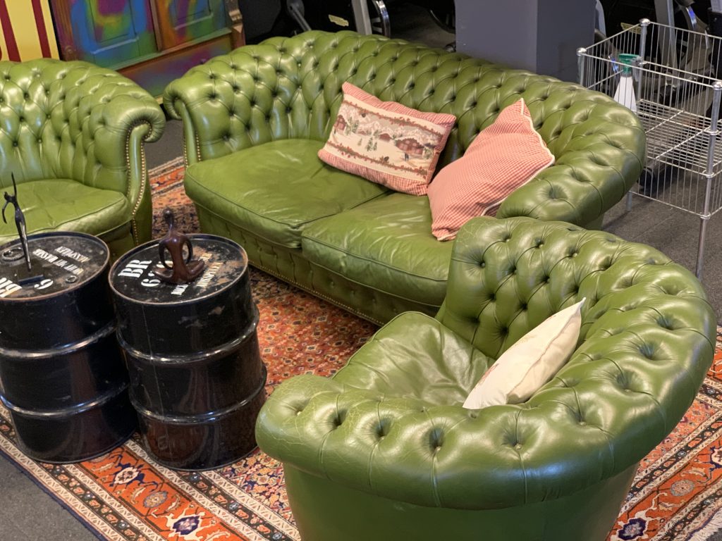 grüne antike Couch mit 2 alten schwarzen Fässern als Tisch
